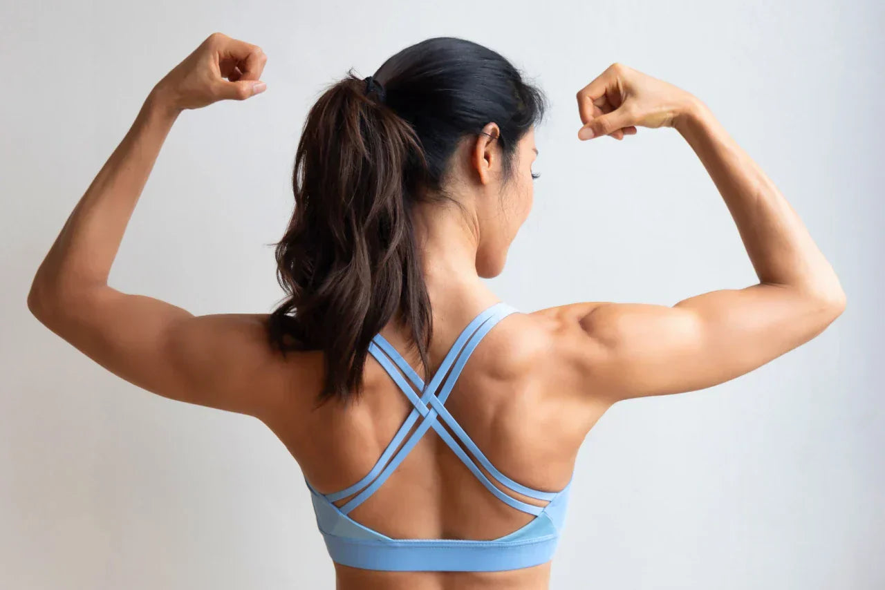 A view of an athletic woman from behind, flexing her muscles.