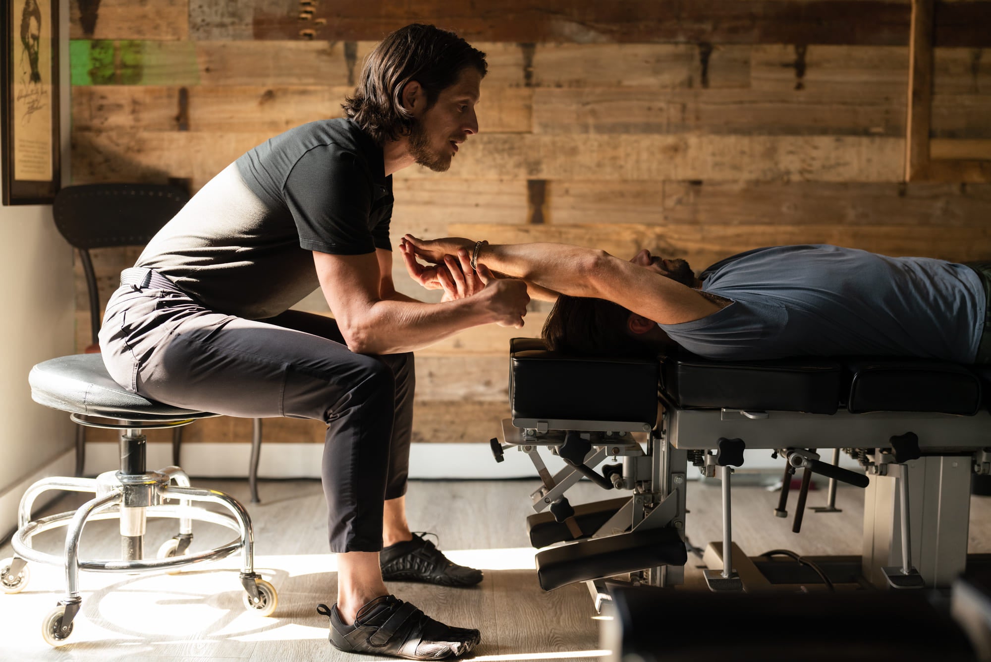 An image of Dr. Palmer performing chiropractic arm adjustment for a man laying on a chiropractic table.