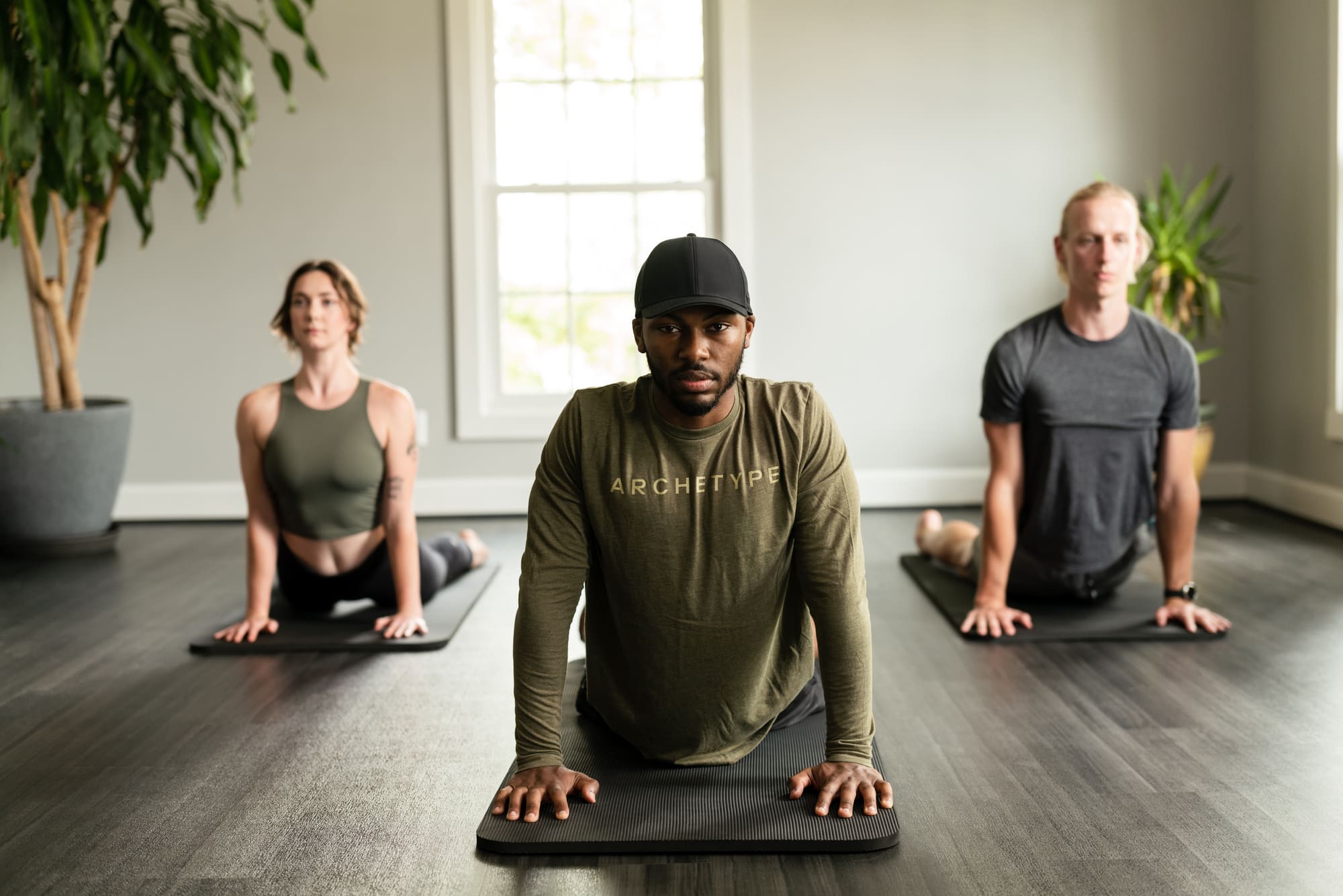 An image of a man wearing a dark green Archetype shirt while completing stretching exercises.